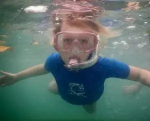 Snorkeling-kid-facing-camera-surface-eco2-diving-mtwara-tanzania Snorkeling girl kid with blue rashguard facing at the surface during snorkeling excursions with Eco2 Diving Mtwara Tanzania